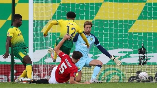 Pemain Manchester United Harry Maguire mencetak gol ke gawang Norwich City dalam pertandingan perempat final Piala FA yang berlangsung di Carrow Road, Sabtu (27/6/2020). [AFP]