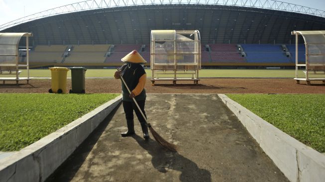 Petugas melakukan perawatan rutin di lapangan Stadion Gelora Sriwijaya Jakabaring Palembang, Sumatera Selatan, Minggu (28/6). [ANTARA FOTO/Feny Selly]