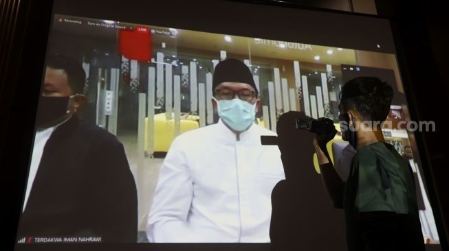 Jurnalis mengambil gambar dari layar yang menyiarkan secara "live streaming" sidang vonis terdakwa mantan Menteri Pemuda dan Olahraga Imam Nahrawi di Gedung KPK, Jakarta, Senin (29/6). [Suara.com/Angga Budhiyanto]