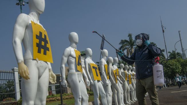 Aktivis Greenpeace menyemprotkan cairan disinfektan pada manekin saat aksi damai menolak pembahasan RUU Cipta Kerja di depan Kompleks Parlemen, Senayan, Jakarta, Senin (29/6). [ANTARA FOTO/Aditya Pradana Putra]