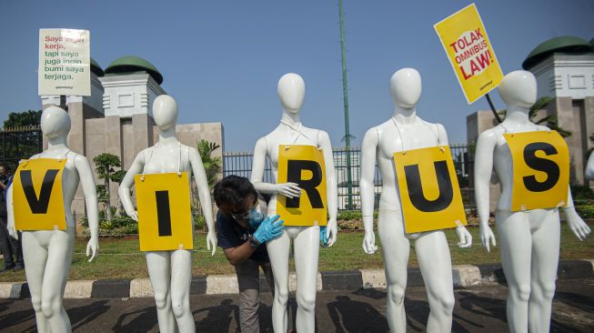 Aktivis Greenpeace memasang poster pada manekin saat aksi damai menolak pembahasan RUU Cipta Kerja di depan Kompleks Parlemen, Senayan, Jakarta, Senin (29/6). [ANTARA FOTO/Aditya Pradana Putra]