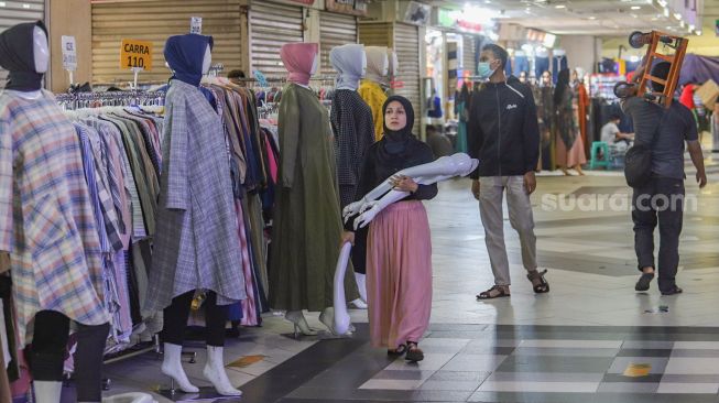 Pedagang membawa tangan manekin di Blok B Pasar Tanah Abang, Jakarta Pusat, Selasa (30/6). [Suara.com/Alfian Winanto]