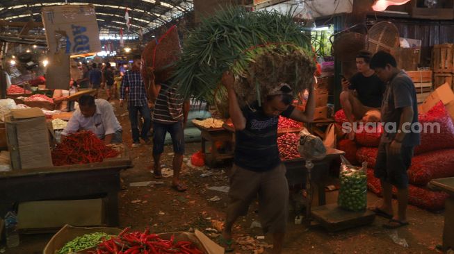 Pedagang membawa sayuran di Pasar Induk Kramat Jati, Jakarta Timur, Selasa (30/6). [Suara.com/Alfian Winanto]
