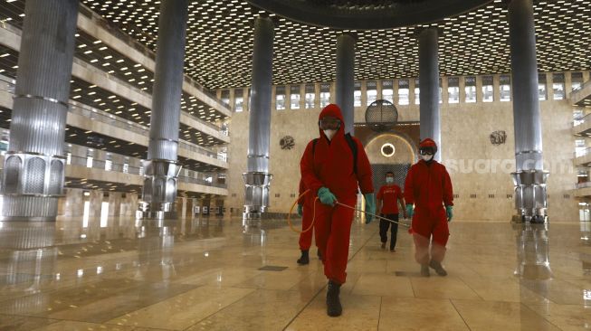 Petugas pemadam kebakaran melakukan penyemprotan cairan disinfektan di Masjid Istiqlal, Jakarta, Rabu (3/6). [Suara.com/Angga Budhiyanto]  