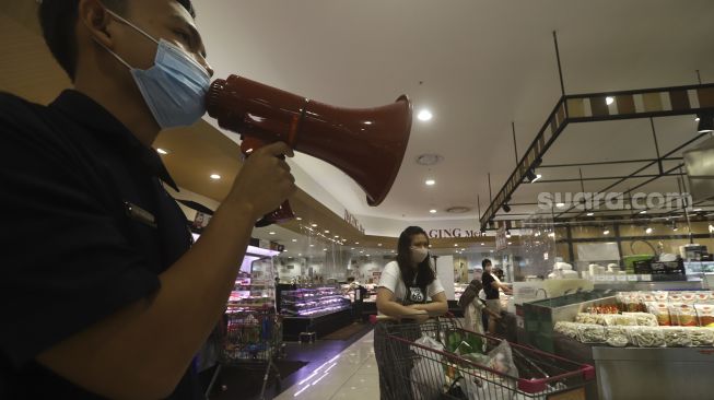 Petugas memberi imbauan kepada pengunjung untuk tetap menjaga jarak fisik saat berbelanja di AEON Mall, Tangerang, Banten, Selasa (2/6). [Suara.com/Angga Budhiyanto