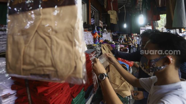 Pedagang seragam sekolah melayani pembeli di Pasar Jatinegara, Jakarta, Selasa (30/6). [Suara.com/Angga Budhiyanto]