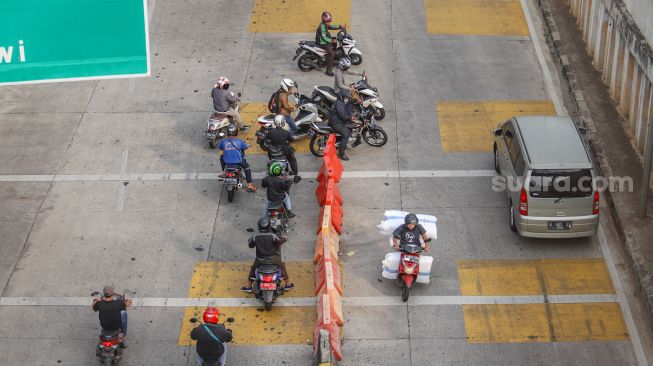 Pengendara motor berputar balik dan melawan arah di depan Gerbang Tol Ciledug, Jakarta Selatan, Rabu (1/7).  [Suara.com/Alfian Winanto]