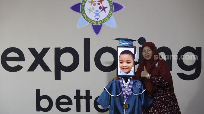 Kepala Sekolah berfoto bersama siswa Kelompok Bermain Taman Kanak-kanak (KB TK) saat wisuda virtual menggunakan Roboda (Robot Wisuda) di Sekolah Nasional Satu (Nassa School), Bekasi, Jawa Barat, Rabu (1/7). [Suara.com/Angga Budhiyanto]
