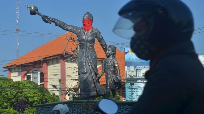 A motorcyclist crosses beside the statue of Raden Ajeng Kartini with a mask in Jepara, Central Java, Wednesday (1/7/2020). [ANTARA FOTO/Yusuf Nugroho]