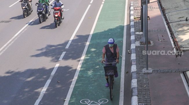 Pekerja menggunakan sepeda melintas di lajur khusus sepeda Jl. MH Thamrin, Jakarta Pusat, Rabu (1/7). [Suara.com/Alfian Winanto]