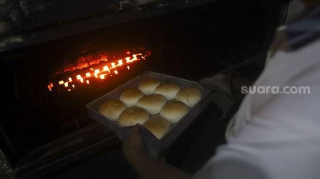 Pekerja mengeluarkan roti dari mesin pemanggang di rumah produksi roti di kawasan Bendungan Hilir, Jakarta, Jumat (3/7). [Suara.com/Angga Budhiyanto]