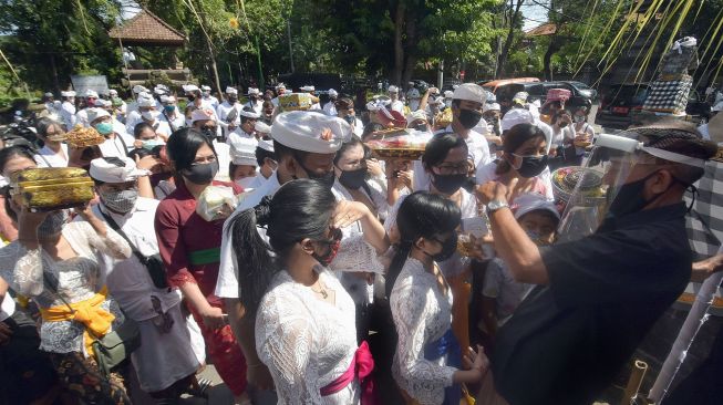 Pecalang atau petugas keamanan desa adat Bali memeriksa suhu tubuh umat Hindu menjelang persembahyangan Hari Saraswati di Pura Agung Jagatnatha, Denpasar, Bali, Sabtu (4/7/2020).  [ANTARA FOTO/Nyoman Hendra Wibowo]