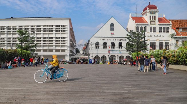 Wisatawan bermain di  kawasan Kota Tua, Jakarta Barat, Sabtu (4/7).  [Suara.com/Alfian Winanto]