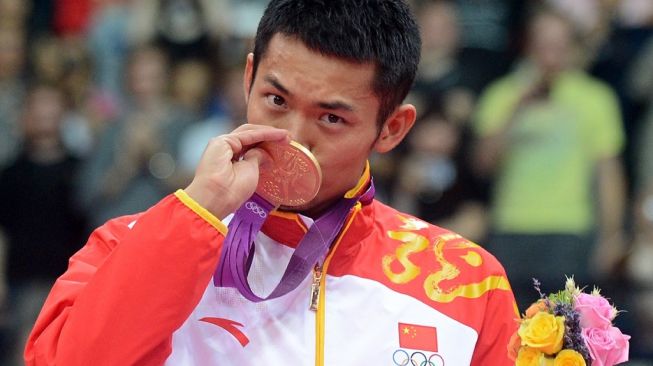 Legenda bulutangkis China Lin Dan mencium medali emas Olimpiade 2012 London. [AFP/Adek Berry]