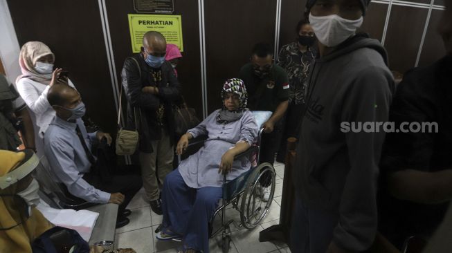  Istri tersangka ujaran kebencian Ruslan Buton, Erna Yudhiana menggunakan kursi roda meninggalkan ruang sidang usai menghadiri sidang praperadilan penetapan status tersangka suaminya di Pengadilan Negeri Jakarta Selatan, Senin (6/7). [Suara.com/Angga Budhiyanto]