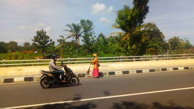 Pertiyem menyapu jalan layang di Kalurahan Sentolo, Kapanewon Sentolo, Kulon Progo, Senin (6/7/2020). - (SuaraJogja.id/Hiskia Andika)