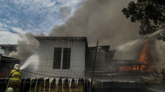 Petugas pemadam kebakaran bersama warga berusaha memadamkan api yang membakar sejumlah toko di Jalan Minangkabau Barat, Manggarai, Jakarta, Selasa (7/7/2020).  [ANTARA FOTO/Galih Pradipta]