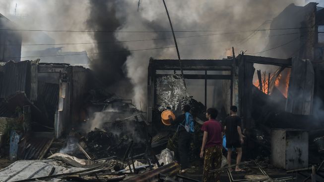Warga berusaha memadamkan api yang membakar sejumlah toko di Jalan Minangkabau Barat, Manggarai, Jakarta, Selasa (7/7/2020).  [ANTARA FOTO/Galih Pradipta]
