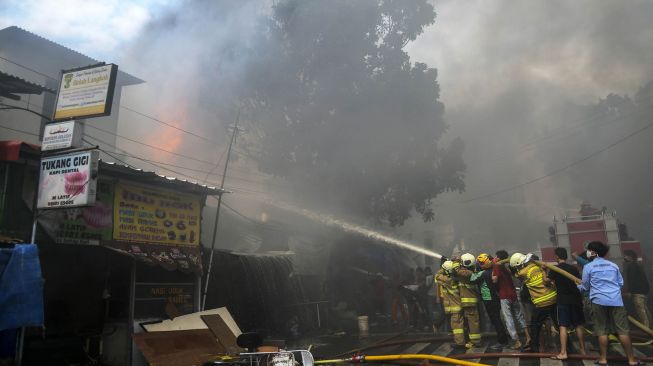 Petugas pemadam kebakaran bersama warga berusaha memadamkan api yang membakar sejumlah toko di Jalan Minangkabau Barat, Manggarai, Jakarta, Selasa (7/7/2020).  [ANTARA FOTO/Galih Pradipta]