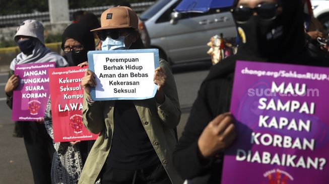 Massa yang tergabung dalam Gerak Perempuan membawa poster penolakan saat melakukan aksi unjuk rasa di depan gedung Dewan Perwakilan Rakyat Republik Indonesia (DPR RI), Jakarta, Selasa (7/7). [Suara.com/Angga Budhiyanto]