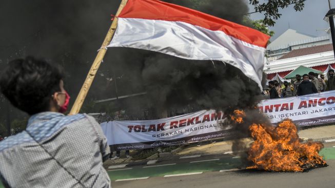 Mahasiswa yang tergabung dalam Gerakan Nasional Tolak Reklamasi (Gentar) Jakarta mengibarkan bendera merah putih saat melakukan aksi unjuk rasa di depan gedung Balai Kota, Jakarta, Rabu (8/7/2020).  [ANTARA FOTO/Galih Pradipta]