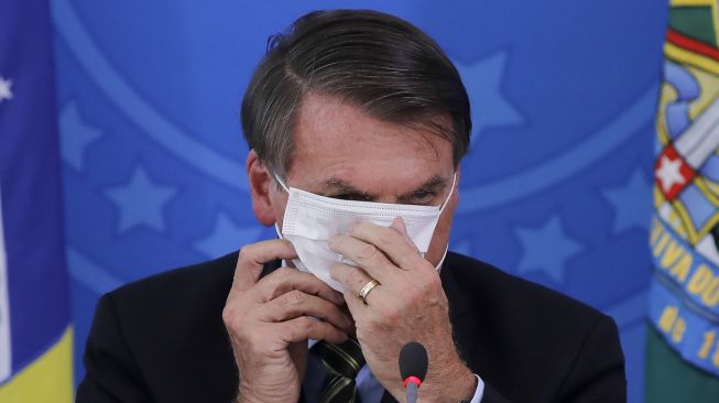 Presiden Brasil Jair Bolsonaro menutupi wajahnya dengan masker selama konferensi pers mengenai pandemi virus COVID-19, pandemi di Istana Planalto, Brasil. File foto ini diambil pada 23 Juni 2020. [Sergio LIMA / AFP]