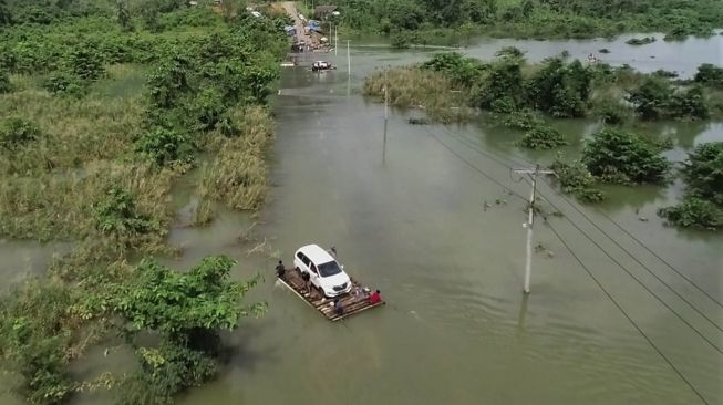 Kendaraan terjebak banjir dan terpaksa diievakuasi dengan menggunakan rakit di jalan trans sulawesi di Desa Sambandete, Kabupaten Konawe Utara, Sulawesi Tenggara, Rabu (8/7/2020).  [ANTARA FOTO/Asrun]