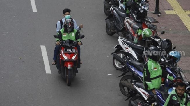 Sebagai ilustrasi PSBB Jakarta: Ojek online membawa penumpang melintas di kawasan Palmerah, Jakarta, Selasa (7/4). [Suara.com/Angga Budhiyanto]