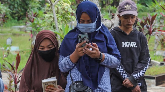 Keluarga berdoa di pemakaman Papa T Bob di TPBU Jurang Mangu, Pondok Ranji, Tangerang Selatan, Jumat (10/7). [Suara.com/Alfian Winanto]
