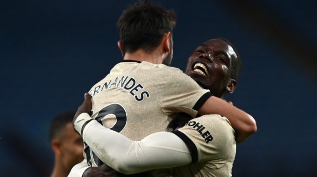 Usai mencetak gol, gelandang Manchester United, Paul Pogba memeluk gelandang Bruno Fernandes pada laga Liga Inggris 2019/2020 kontra Aston Villa di Villa Park, Birmingham, Jumat (10/7/2020) dini hari WIB. [Shaun Botterill / POOL / AFP]