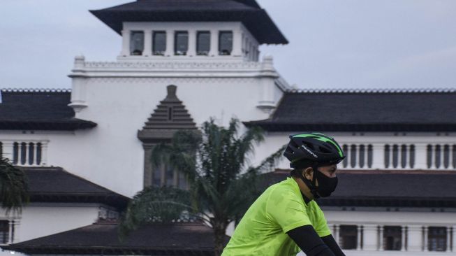 Warga mengenakan masker saat bersepeda di depan Gedung Sate, Bandung, Jawa Barat, Kamis (9/7/2020).  [ANTARA FOTO/Novrian Arbi]