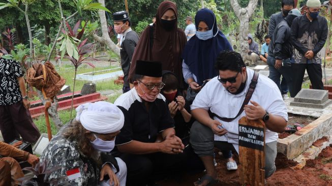 Keluarga berdoa disamping pusara almarhum pencipta lagu anak-anak, Papa T Bob di TPBU Jurang Mangu, Pondok Ranji, Tangerang Selatan, Jumat (10/7). [Suara.com/Alfian Winanto]
