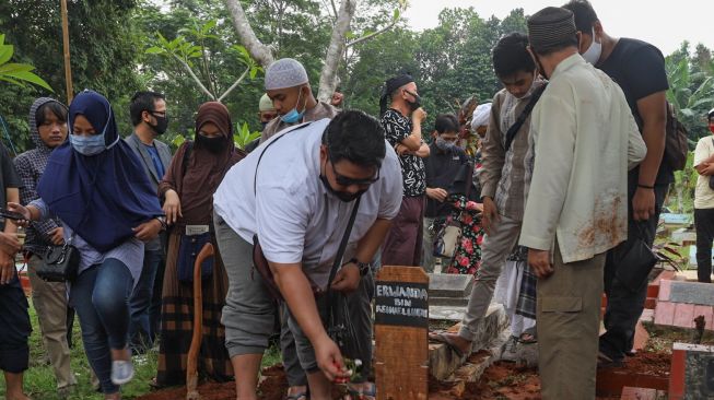 Keluarga menaruh bunga di pusara Papa T Bob di TPBU Jurang Mangu, Pondok Ranji, Tangerang Selatan, Jumat (10/7). [Suara.com/Alfian Winanto]
