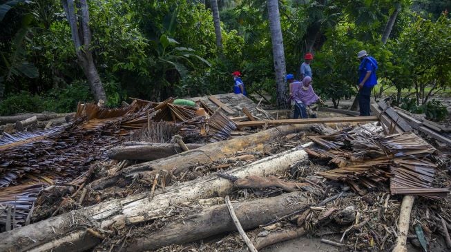 Warga melintas di dekat puing rumah yang hancur akibat diterjang banjir bandang di Desa Oloboju, Kabupaten Sigi, Sulawesi Tengah, Sabtu (11/7). [ANTARA FOTO/Basri Marzuki]