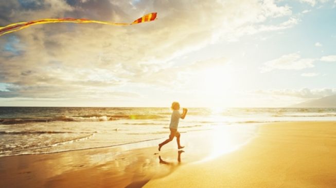 Main layang-layang di pantai. (shutterstock)