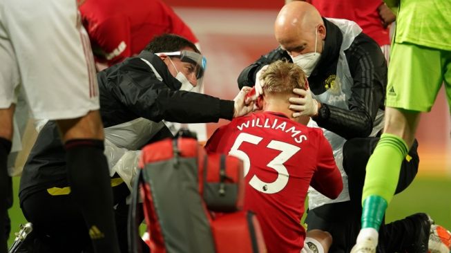 Fullback Manchester United, Brandon Williams mendapatkan perawatan dalam laga Liga Inggris 2019/2020 kontra Southampton di Old Trafford, Selasa (14/7/2020) dini hari WIB. [DAVE THOMPSON / POOL / AFP]