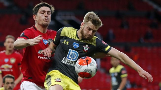 Bek Manchester United, Harry Maguire (kiri) berduel dengan pemain Southampton, Stuart Armstrong pada laga Liga Inggris 2019/2020 di Old Trafford, Selasa (14/7/2020) dini hari WIB. [Clive Brunskill / POOL / AFP]