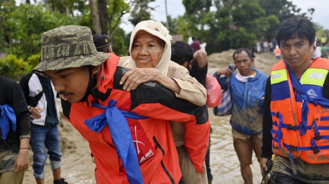 Tim SAR menggendong seorang korban banjir bandang saat dievakuasi di Desa Radda, Kabupaten Luwu Utara, Sulawesi Selatan, Selasa (14/7/2020). [ANTARA FOTO/Hariandi Hafid]