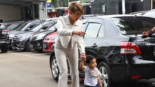 Aktris Nikita Mirzani menggandeng buah hatinya, Arkana Mawardi saat tiba di Pengadilan Negeri Jakarta Selatan, Rabu, (15/7). [Suara.com/Alfian Winanto]