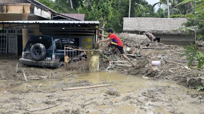 Warga berusaha memeanjat kedalam rumahnya yang tenggelam lumpur akibat banjir bandang di Desa Radda, Kabupaten Luwu Utara, Sulawesi Selatan, Selasa (14/7/2020).  [ANTARA FOTO/Hariandi Hafid