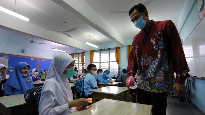 Guru menyemprotkan handsanitizer ke meja sebelum mulai mengajar di Bandar Baru Bangi, Selangor, Malaysia pada 15 Juli 2020. [Foto/ Anadolu Agency]
