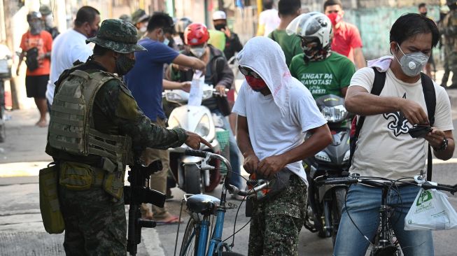 Warga menunjukan kartu identifikasi kepada Polisi di Navotas, pinggiran kota Manila, Filipina, Kamis (16/7).   [Ted ALJIBE / AFP]