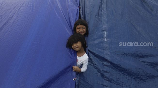 Dua anak warga Kampung Muka bermain di tenda darurat yang didirikan secara mandiri setelah penggusuran pada 15 Juli 2020 lalu di Kawasan Stasiun Kampung Bandan, Jakarta, Jumat (17/7/2020). [Suara.com/Angga Budhiyanto]