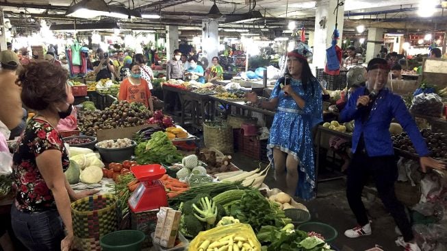 Dua musisi jalanan menggunakan pelindung wajah mengamen di Pasar Tradisional Petisah Medan, Sumatera Utara, Jumat (17/7/2020). [ANTARA FOTO/Septianda Perdana]