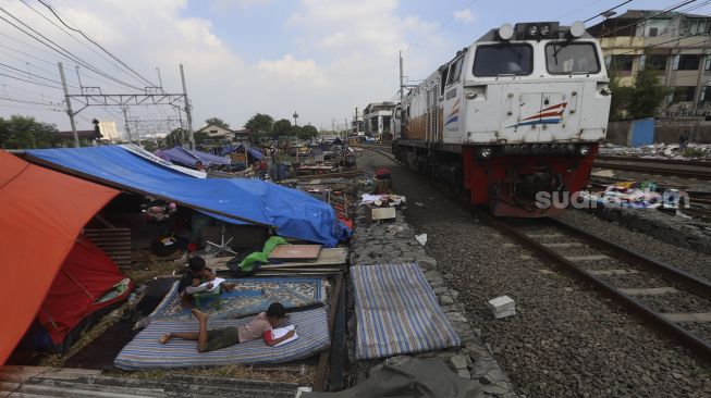 Dua anak warga Kampung Muka belajar di tenda darurat yang didirikan secara mandiri setelah penggusuran pada 15 Juli 2020 lalu di Kawasan Stasiun Kampung Bandan, Jakarta, Jumat (17/7/2020). [Suara.com/Angga Budhiyanto]