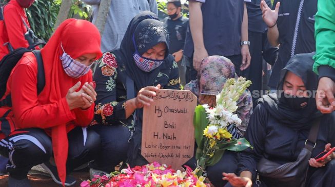 Para pelayat berdoa diatas pusara komedian Omaswati di TPU Cisalak, Cimanggis, Depok, Jawa Barat, Jumat (17/7). [Suara.com/Alfian Winanto]