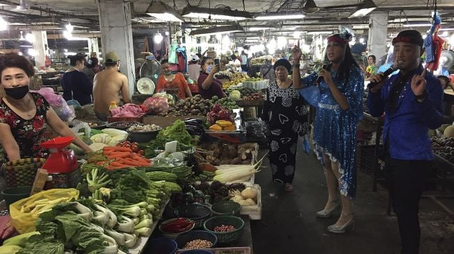 Dua musisi jalanan menggunakan pelindung wajah mengamen di Pasar Tradisional Petisah Medan, Sumatera Utara, Jumat (17/7/2020). [ANTARA FOTO/Septianda Perdana]