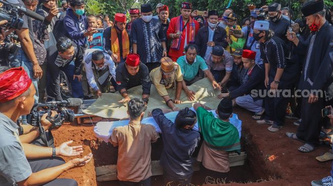 Proses penurunan jenazah komedian Omaswati ke liang lahat di TPU Cisalak, Cimanggis, Depok, Jawa Barat, Jumat (17/7). [Suara.com/Alfian Winanto]