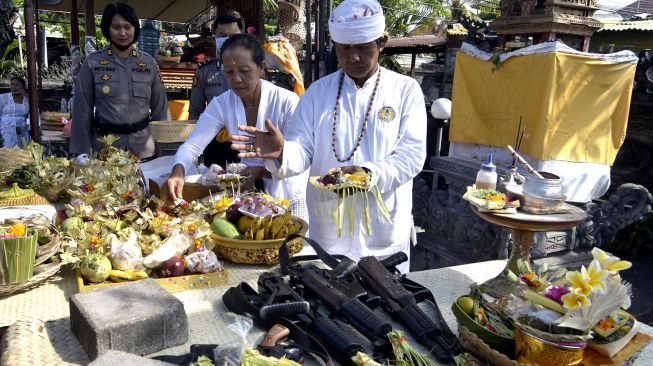 Pemuka agama Hindu dan petugas kepolisian mengupacarai persenjataan saat rangkaian persembahyangan Hari Raya Tumpek Landep di Polsek Denpasar Selatan, Bali, Sabtu (18/7/2020). [ANTARA FOTO/Fikri Yusuf]