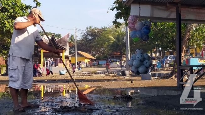 Warga membersihkan sisa material-material yang terbawa saat gelombang tinggi di objek wisata Pantai Karanghawu, Desa Cisolok, Kecamatan Cisolok, Kabupaten Sukabumi, Sabtu (18/7/2020). [Foto: Sukabumiupdate.com]